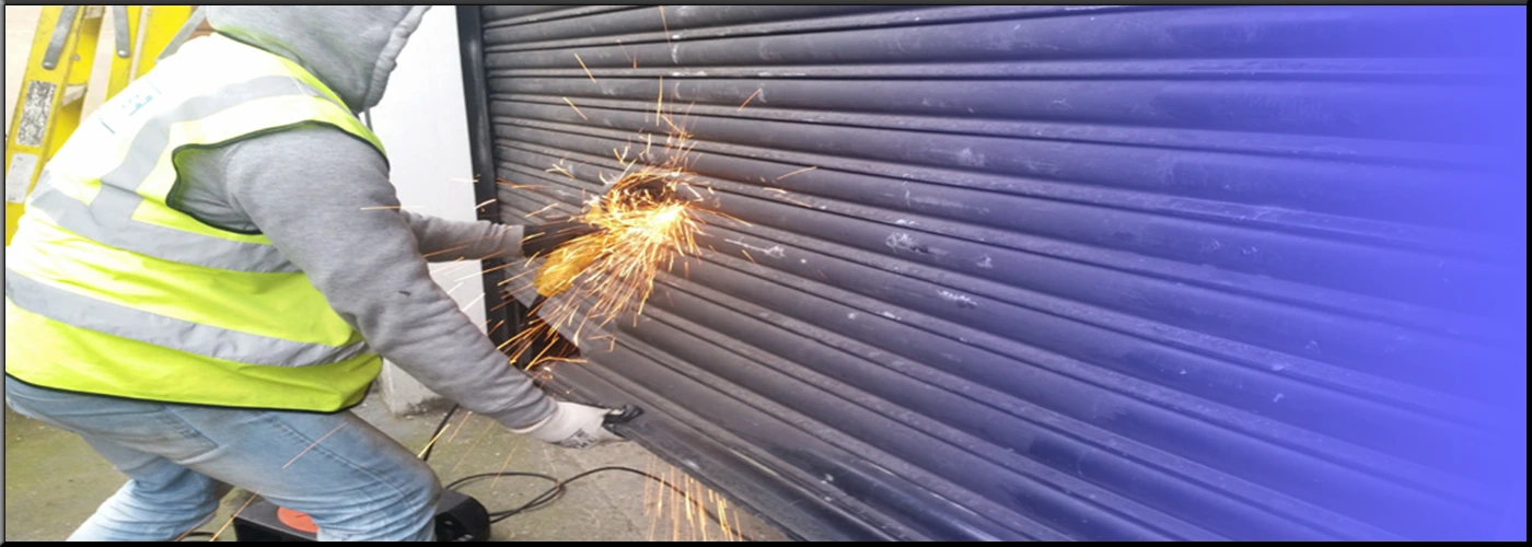 Expert technician meticulously repairing a commercial roller shutter mechanism in Essex